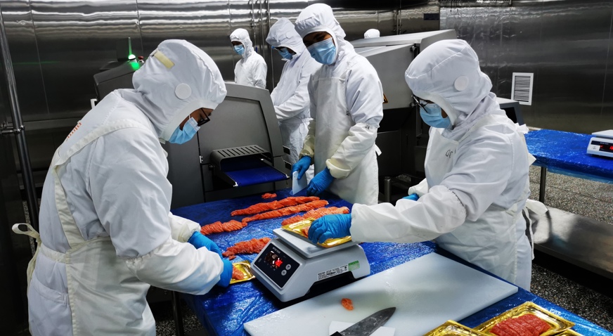 Tianyun employees weigh trout portions with Marel equipment